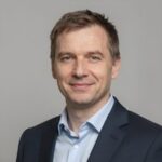 Портрет уверенного российского бизнесмена с дружелюбным взглядом на размытом нейтральном фоне в студии